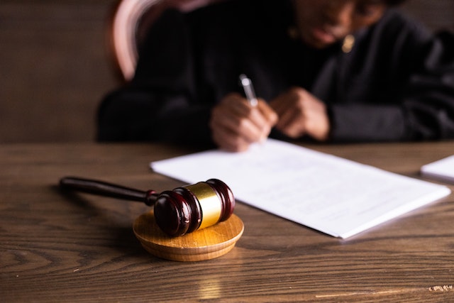 judge writing on a piece of paper with their gavel next to them